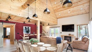 A rustic cabin interior with a dining area, sofa, and fireplace. - Bearly Dreaming Elite Location Hot Tub & Game Room (Gatlinburg)