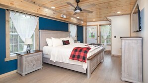 A bedroom with a wooden ceiling, a bed with white bedding, a nightstand, a dresser, and a ceiling fan. - Bearly Dreaming Elite Location Hot Tub & Game Room (Gatlinburg)