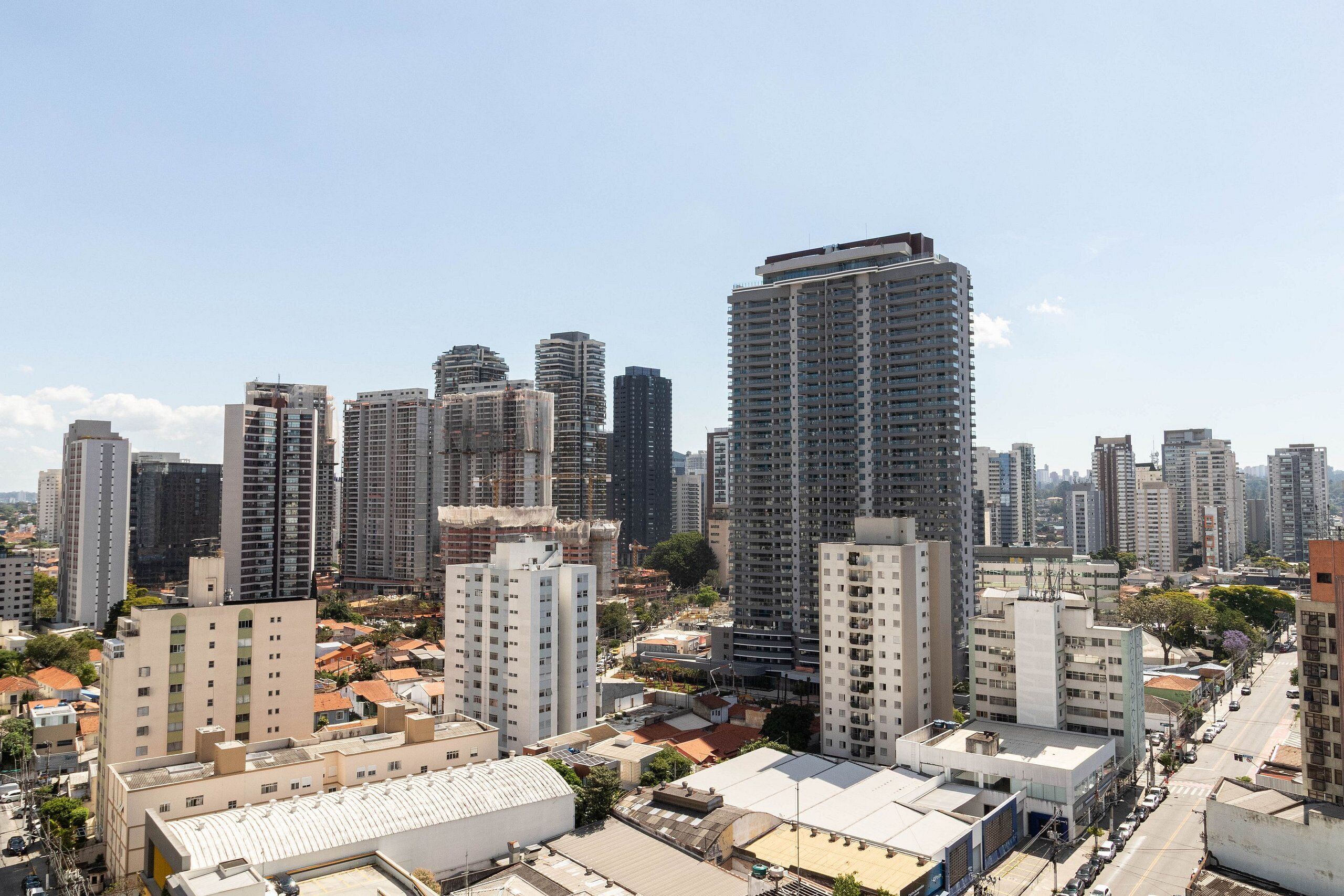 A high-rise urban area with multiple buildings, including a prominent tall building with a flat roof and a smaller building with a curved roof.