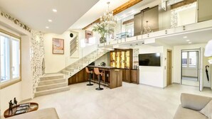 A spacious living area with a staircase, a bar area, and a seating area with a sofa. - Luxury duplex in the heart of Old Antibes (Antibes)