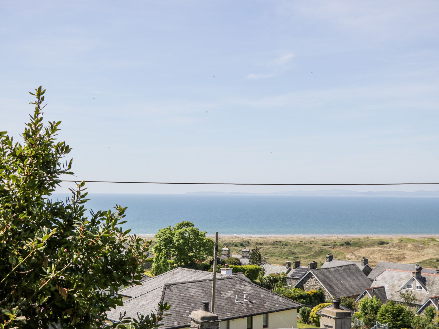 A coastal village with traditional stone houses, a clear view of the sea, and a distant beach.