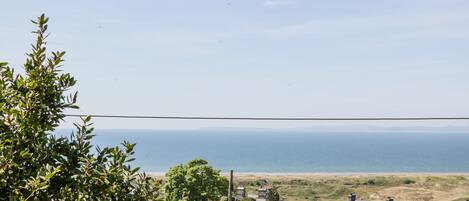 A coastal village with traditional stone houses, a clear view of the sea, and a distant beach.
