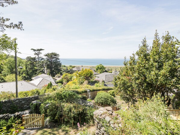 A residential area with houses, a stone wall, and a view of the sea.