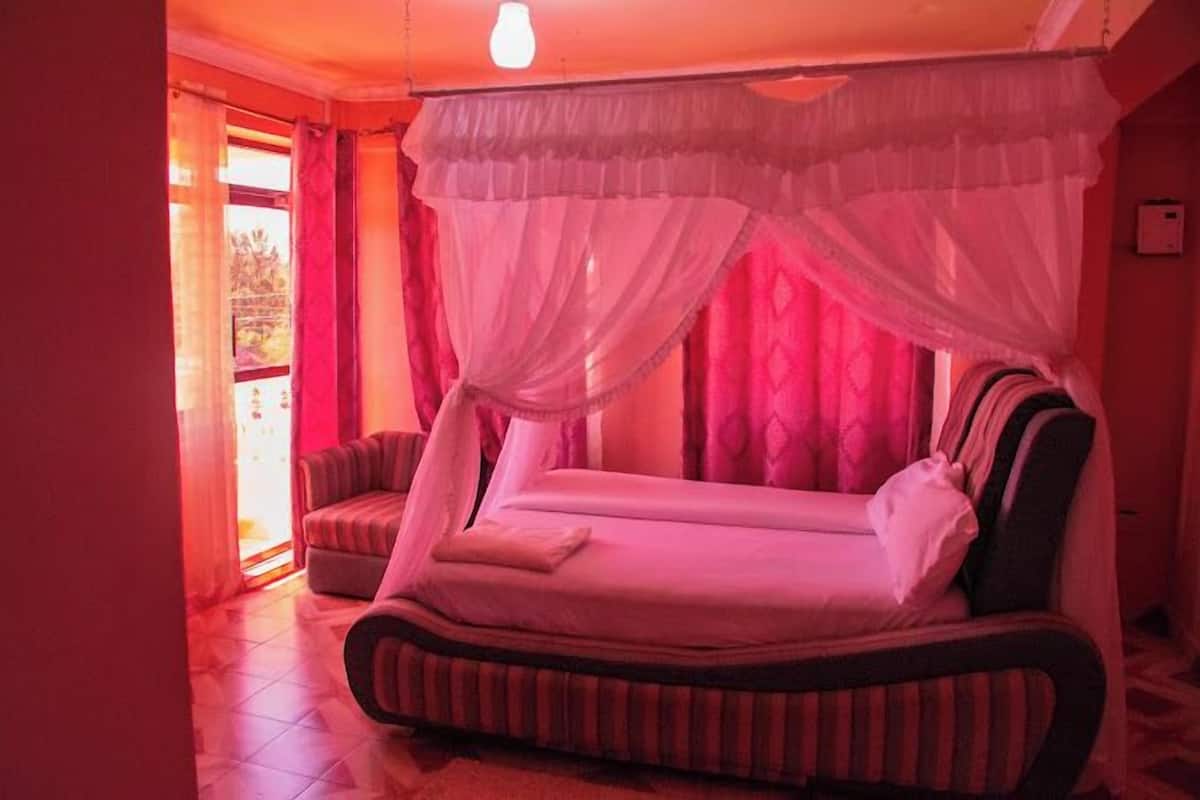 A room with a bed, a chair, and a window with curtains.
