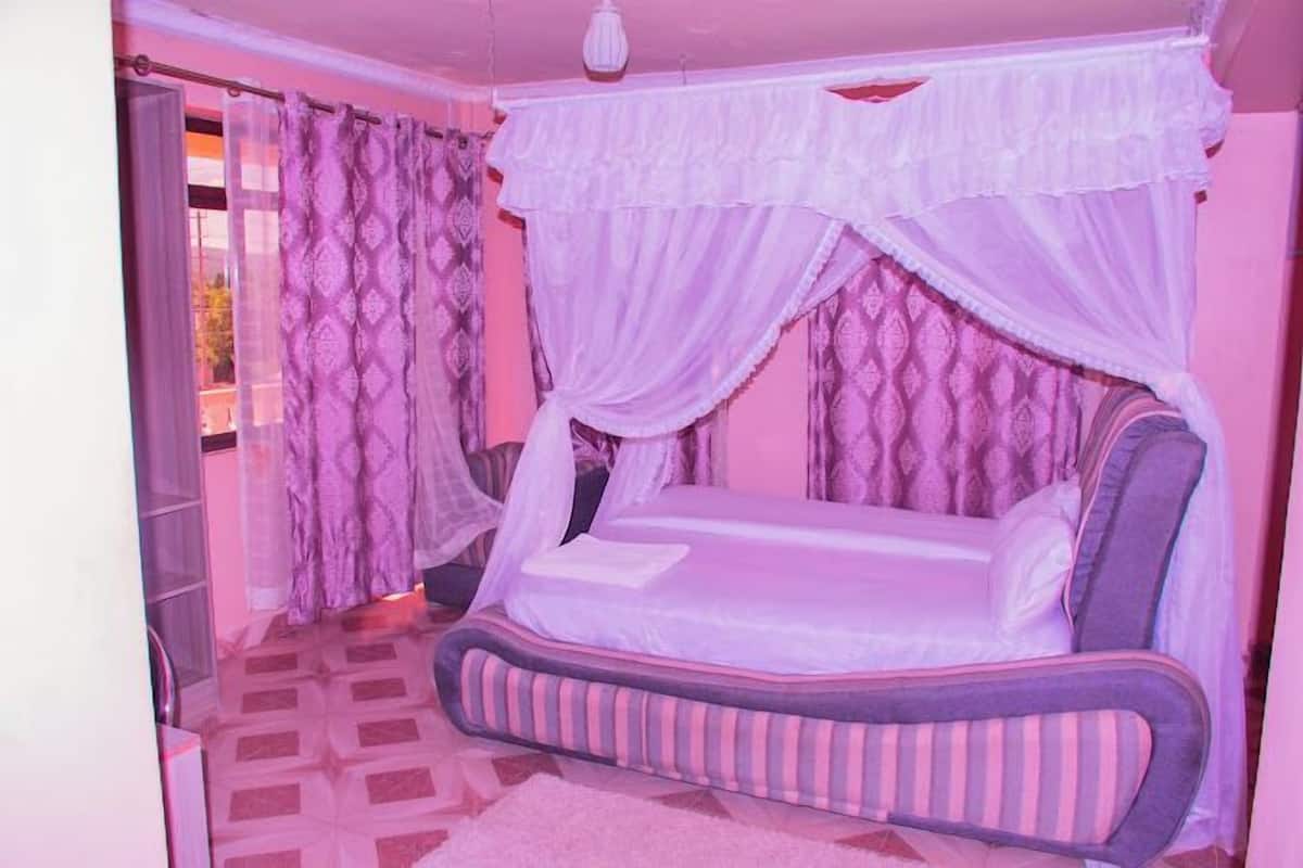 A room with a bed, curtains, and a patterned floor.