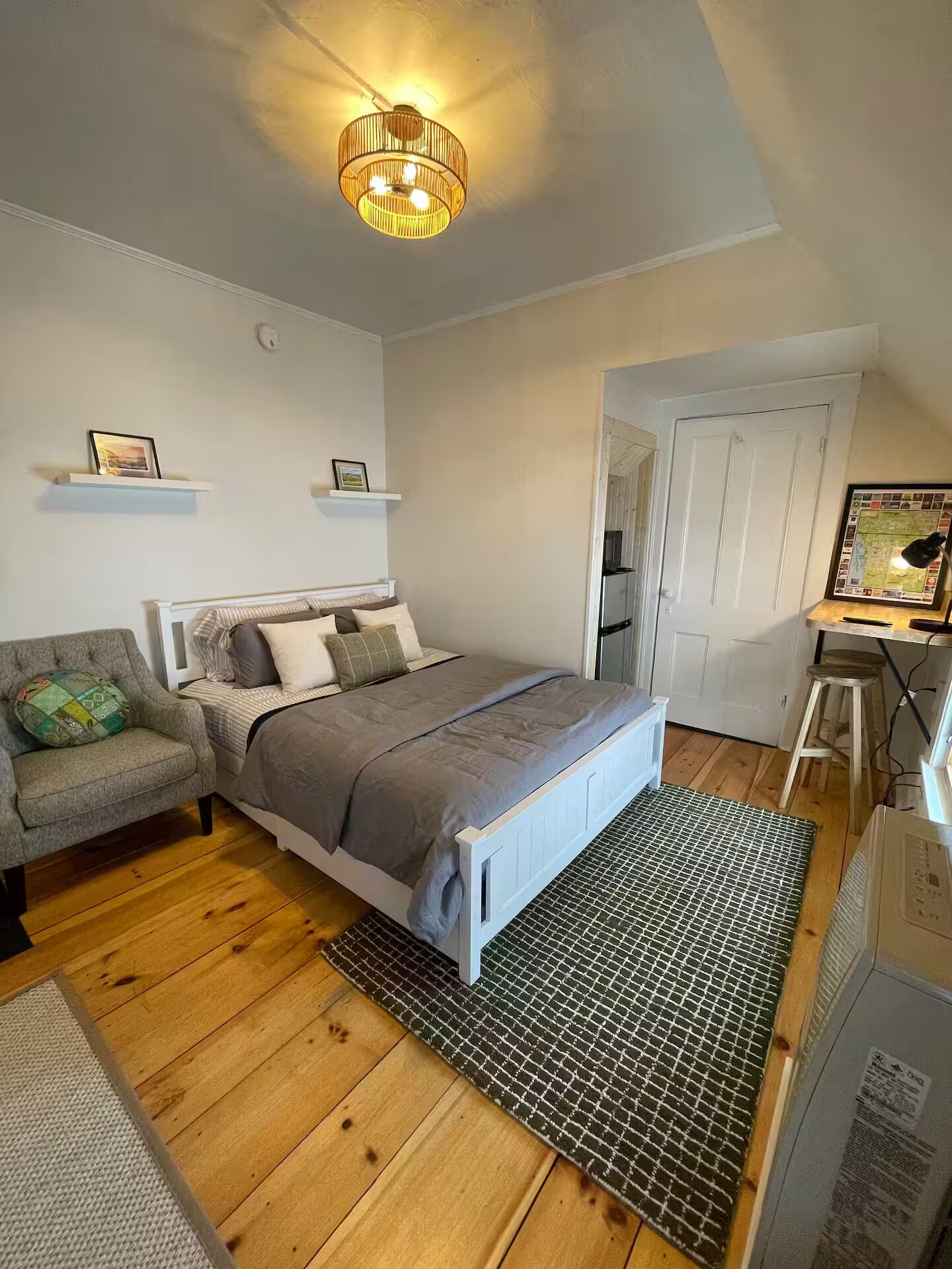 A bedroom with a bed, a chair, a desk, and a map on the wall.