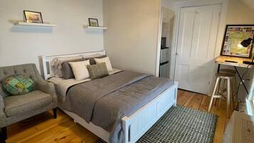 A bedroom with a bed, a chair, a desk, and a map on the wall.