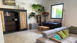 A modern living room with a sofa, a coffee table, a cabinet, and a window with a view of greenery.