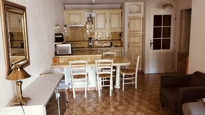 A compact kitchen with a dining area, a white table, and chairs. - Apartment in the port of Hyères (Hyères)