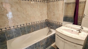 Un baño con bañera, lavamanos y espejo.