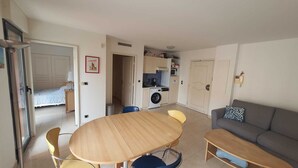 Un espacio habitable compacto con comedor, sofá, lavadora y kitchenette.