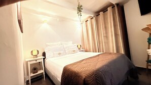 A hotel room with a bed, nightstands, a lamp, and curtains.