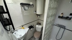 A compact bathroom with a toilet, sink, and shower.