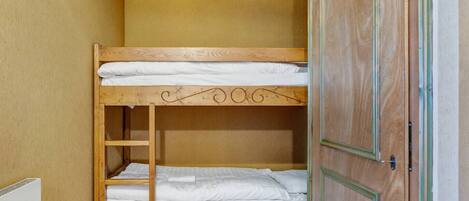 A bunk bed in a room with wooden walls and a door.