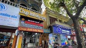 A street scene with various shops, including a visible restaurant named 'Chup Anh Lay Ngay' and a store named 'Suda Ning'. - Heritage Corner Hostel (Hanoi)