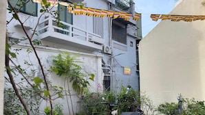 A courtyard with a parked scooter, potted plants, and a building with a balcony. - Heritage Corner Hostel (Hanoi)