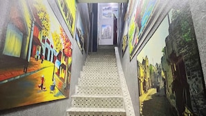 A staircase with colorful murals on both sides, leading to an upper level. - Heritage Corner Hostel (Hanoi)