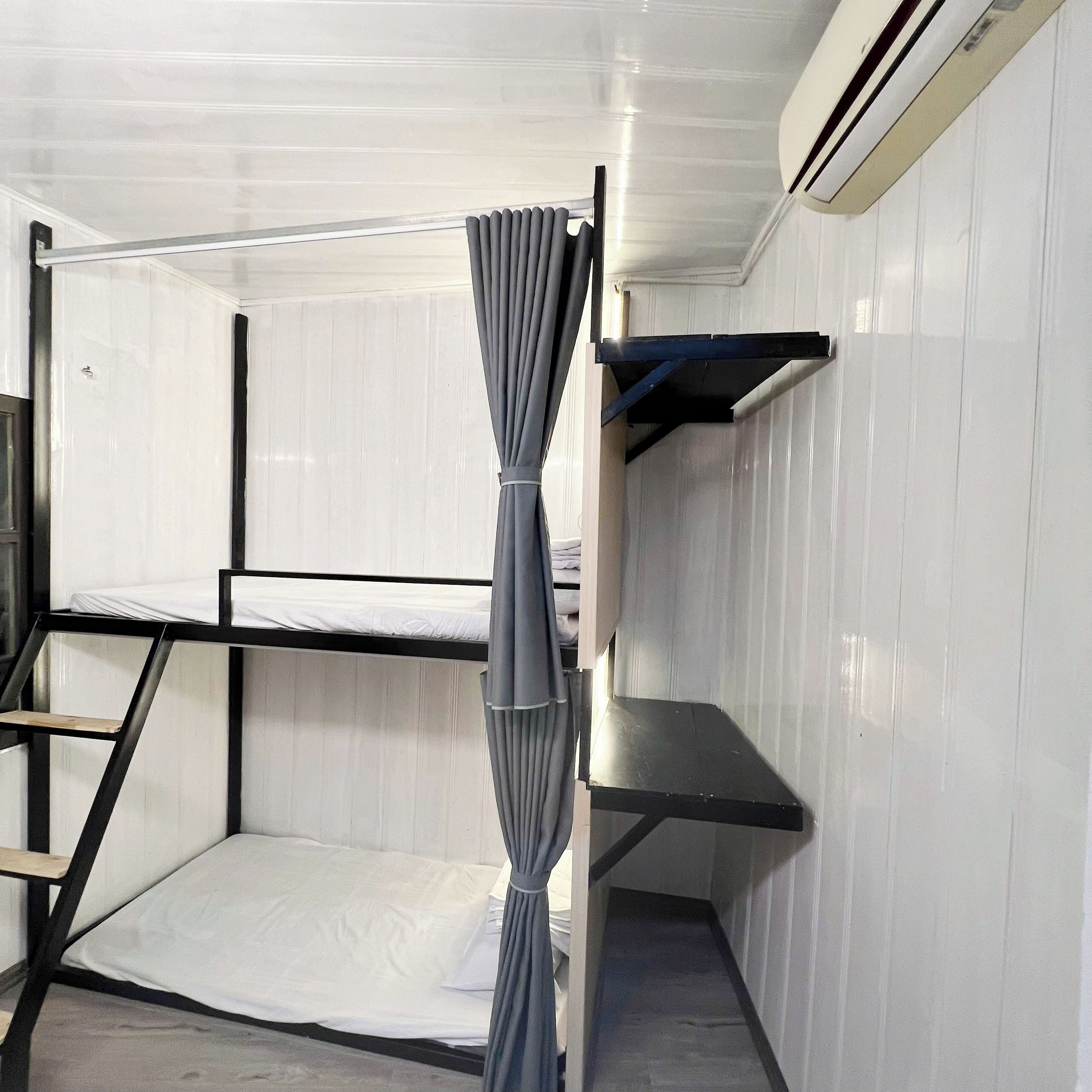 A bunk bed room with a curtain, a shelf, and a ladder.