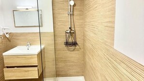 A modern bathroom with a glass shower enclosure, a wooden vanity, and a mirror.