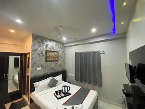 A hotel room with a bed, a ceiling fan, a shower area, and a bathroom visible through a glass door. - Hotel Grandview And coliving (Hyderabad)
