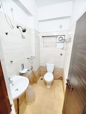 A small, compact bathroom with a toilet, sink, and shower. - Hotel Grandview And coliving (Hyderabad)