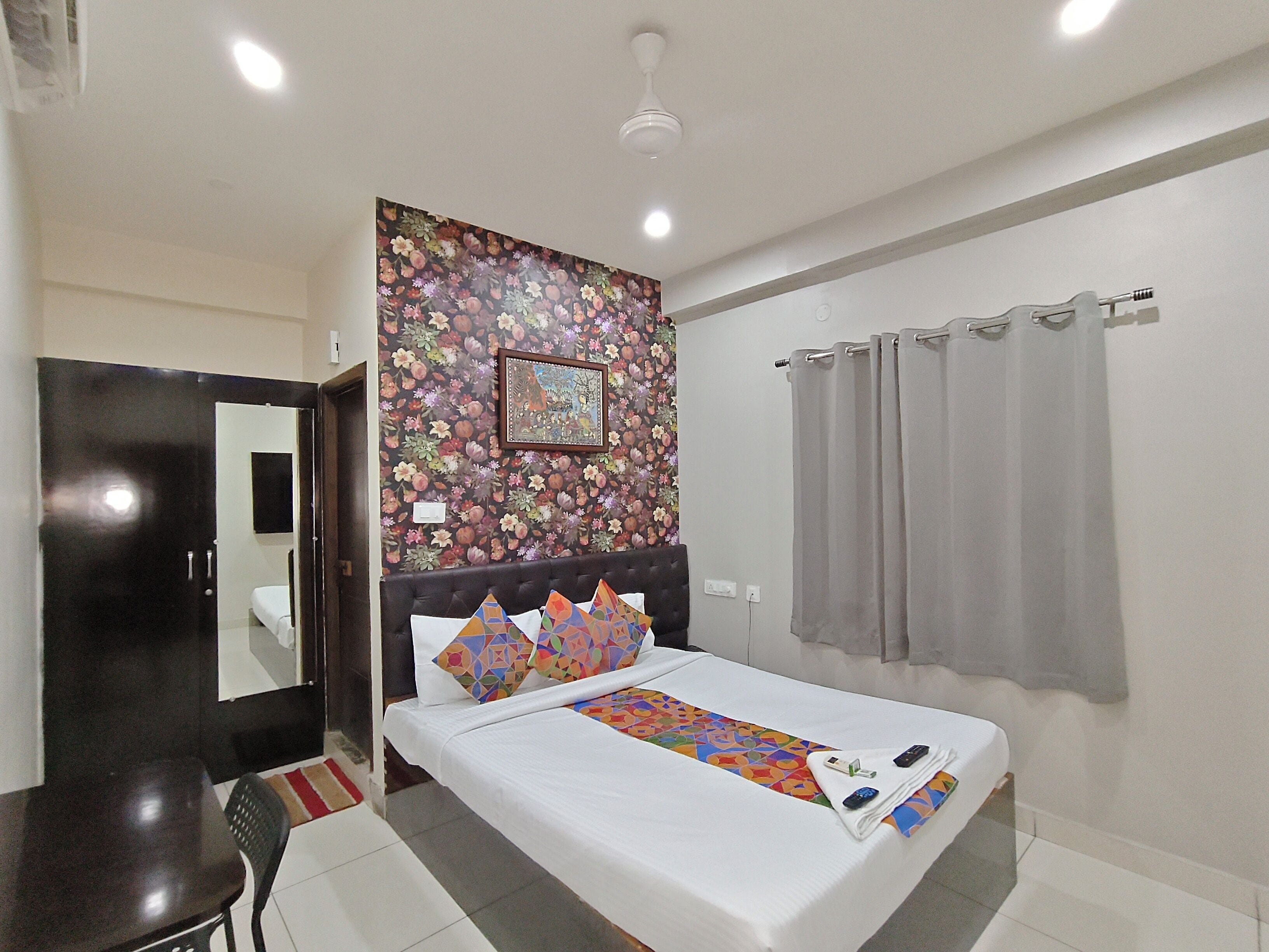 A hotel room with a bed, a desk, a chair, a bathroom, and a shower curtain.