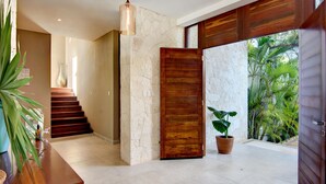 Un interior moderno con una escalera, una puerta de madera y una planta en maceta.