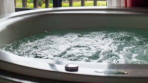 A hot tub with a view of the sea and mountains through a window. - Olhos verdes Guest house (Bombinhas)