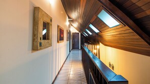 A corridor with wooden ceiling beams, skylights, and a railing. - Olhos verdes Guest house (Bombinhas)