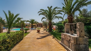 A pathway leading to a pool area with palm trees and a stone structure.