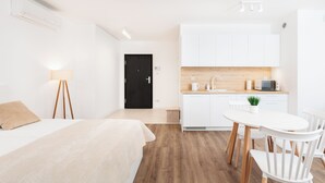 A modern hotel room with a bed, bedside lamp, and a kitchenette with a microwave and sink. - City of the Kings-Riverside WT2 (Kraków)