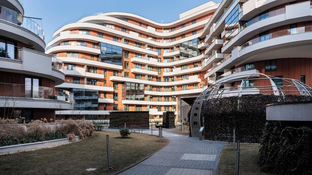 A modern multi-story residential building with curved balconies and a central courtyard. - City of the Kings-Riverside WT2 (Kraków)