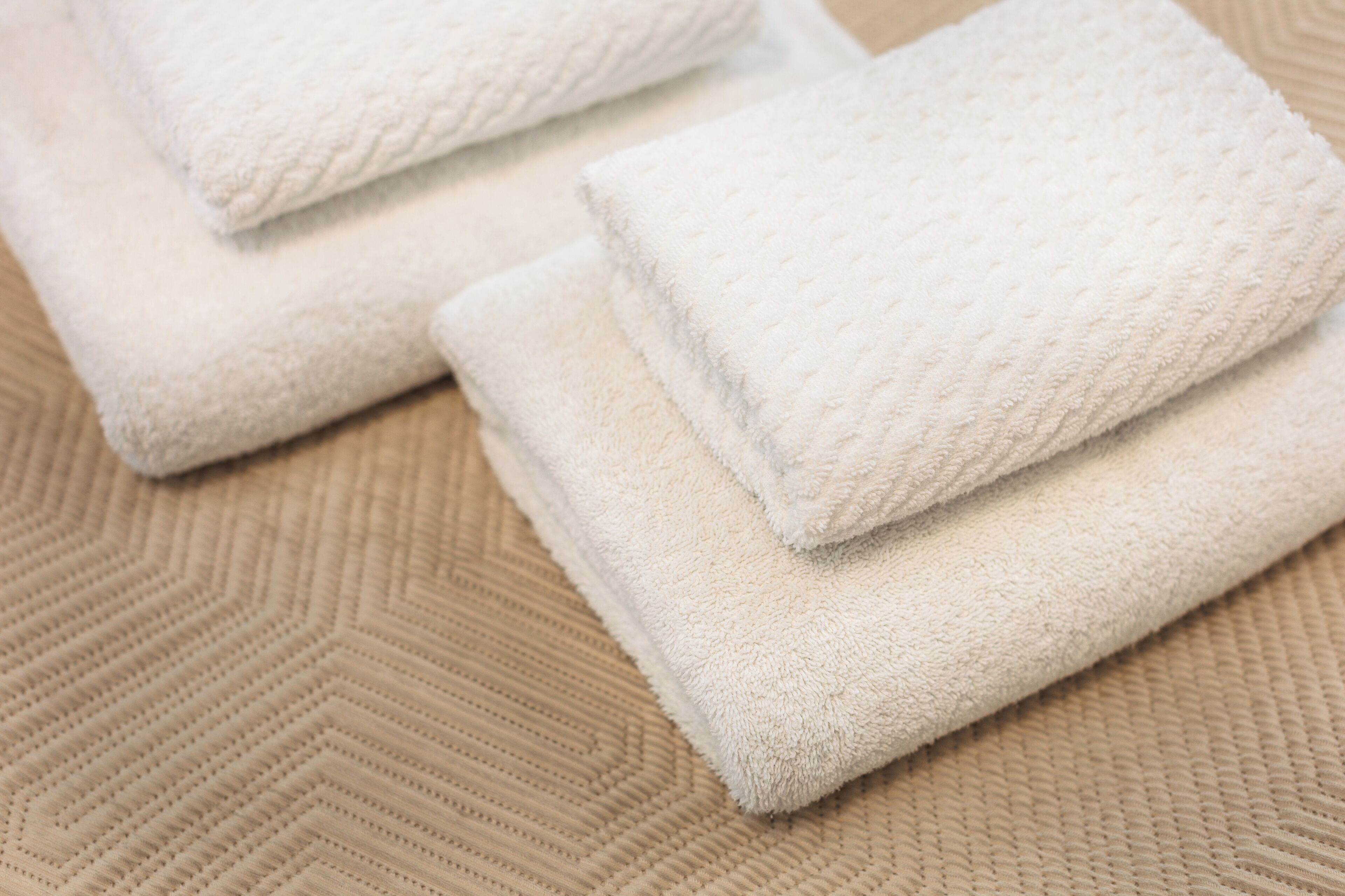 A stack of white towels on a beige textured surface.