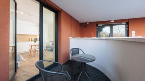 A balcony with a glass door leading to a kitchen, a small table, and two chairs. - City of the Kings-Riverside WT2 (Kraków)