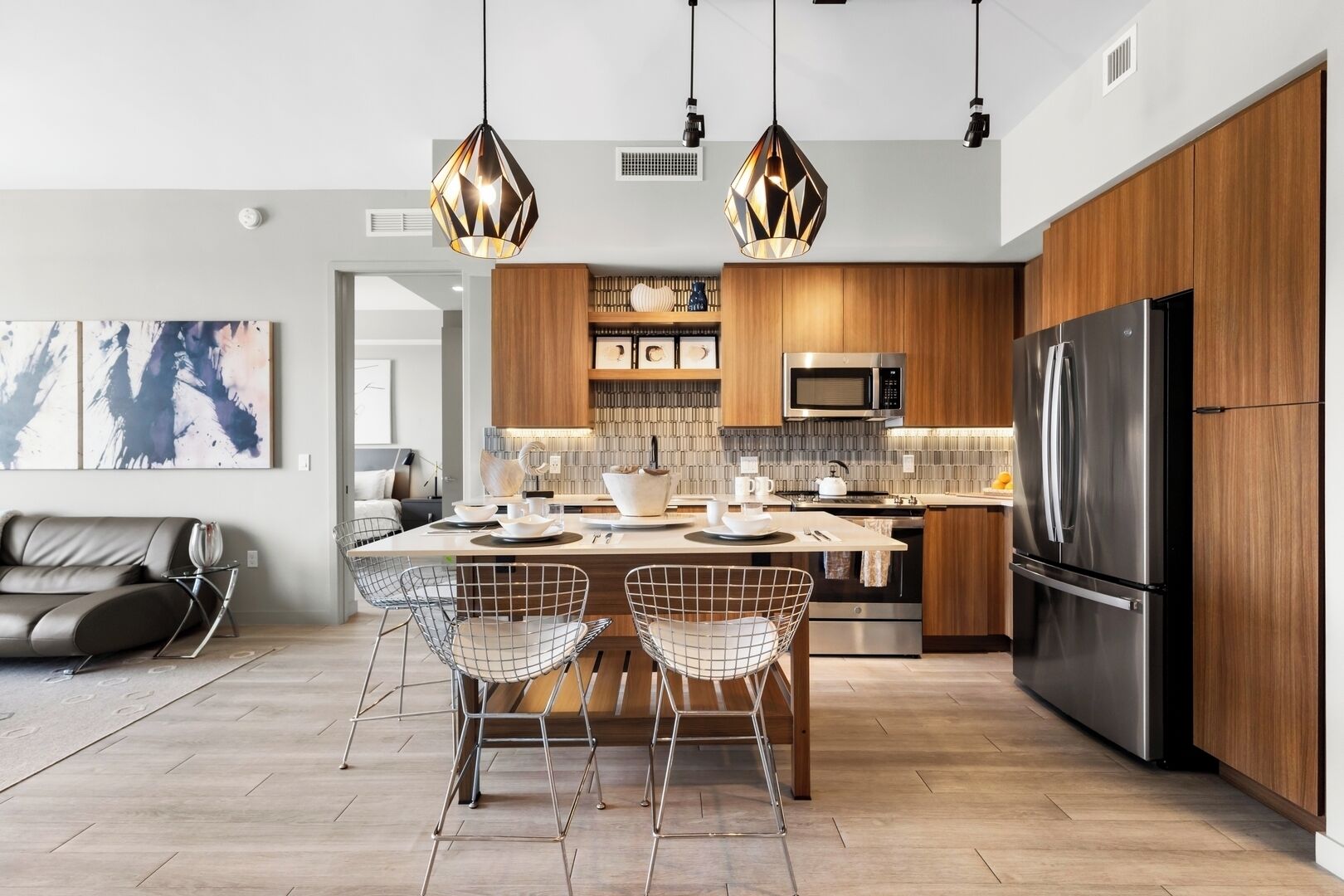 Una cocina moderna con una isla central, electrodomésticos de acero inoxidable e iluminación colgante.