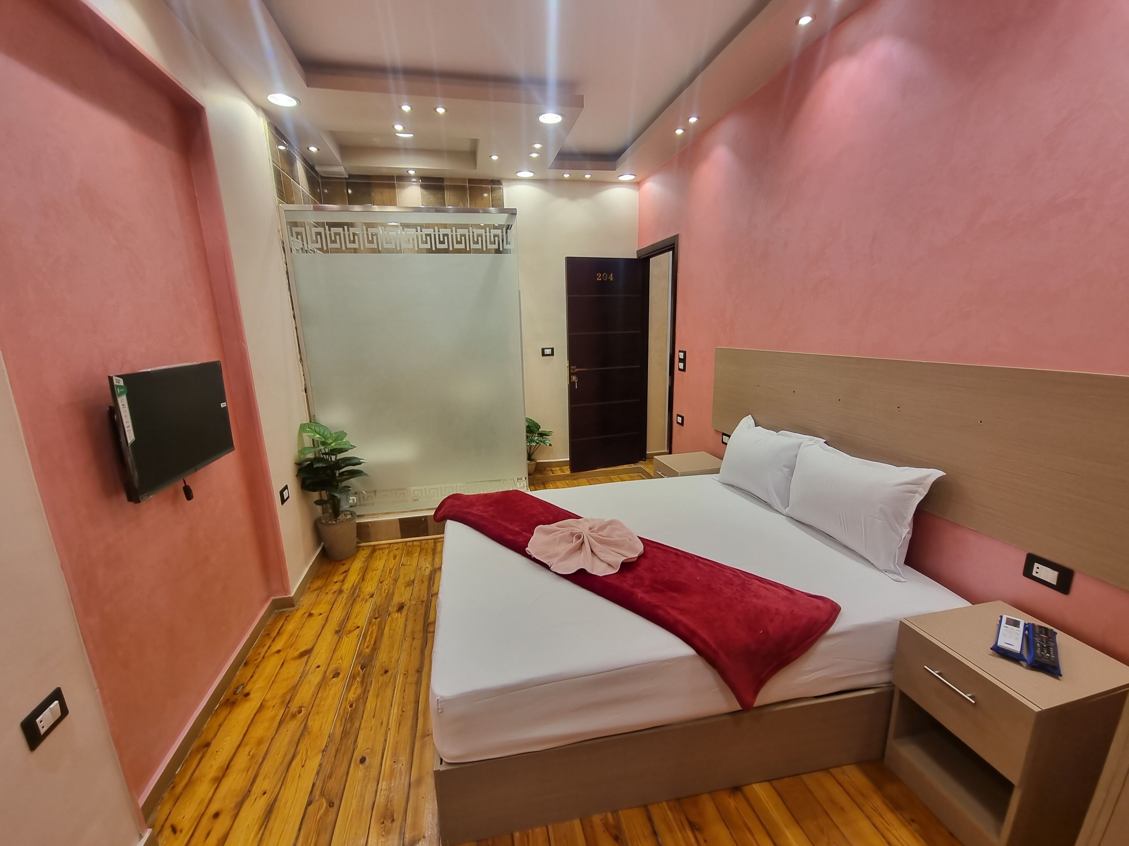 A hotel room with a bed, bedside table, and a television mounted on the wall.