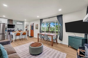 A modern kitchen with a dining area, a flat-screen TV, and a view of the outdoors. - Lakefront Getaway For 4 with Swimming, Kayaks (Snohomish)