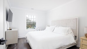 Une chambre d’hôtel moderne dotée d’un grand lit, d’un téléviseur à écran plat fixé au mur et d’une fenêtre donnant sur l’extérieur.