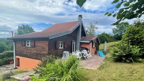 A rustic house with a sloped roof, a chimney, and a small porch. - Nature chalet on 8000m2 of totally quiet land in Coinchimont (Ban-de-Laveline)