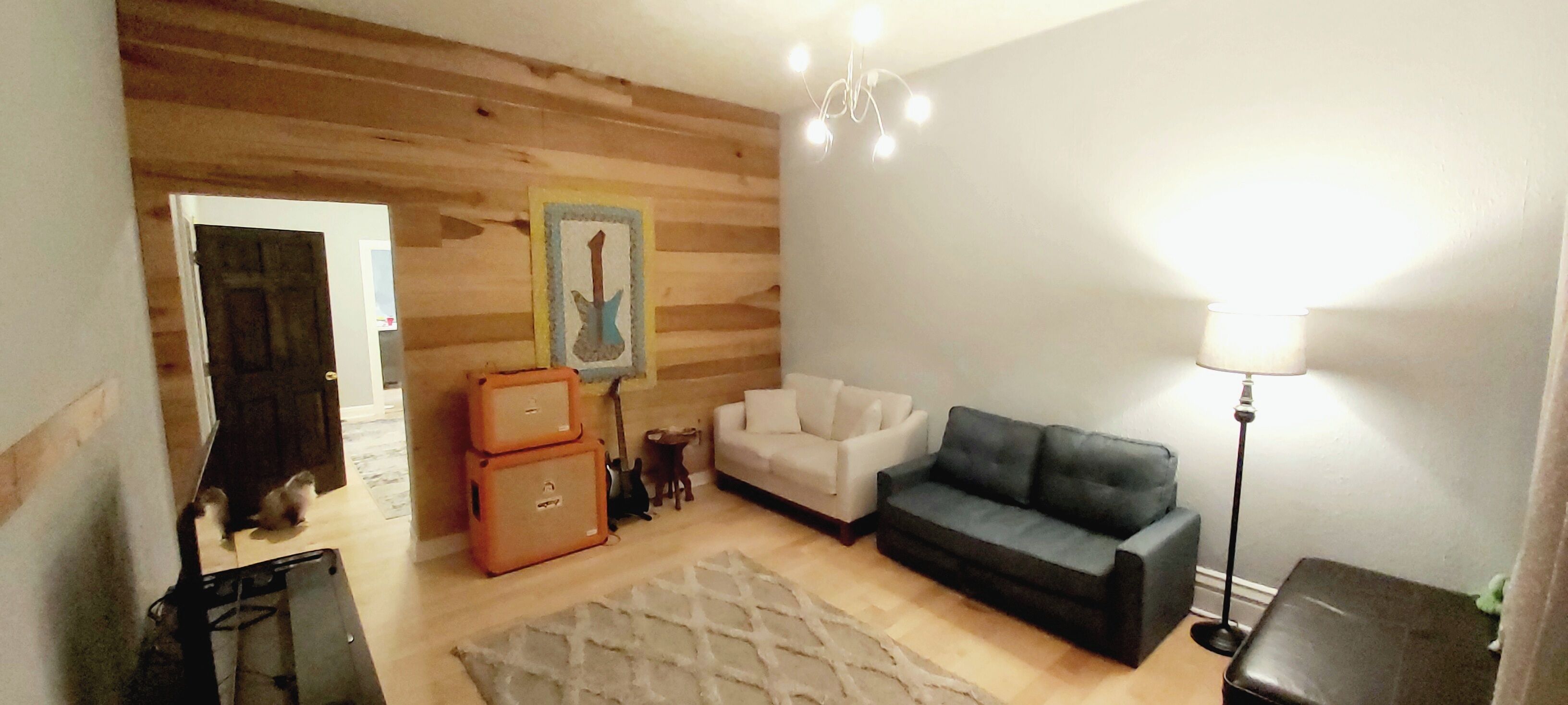 A living room with a white sofa, a dark sofa, a lamp, and a guitar.