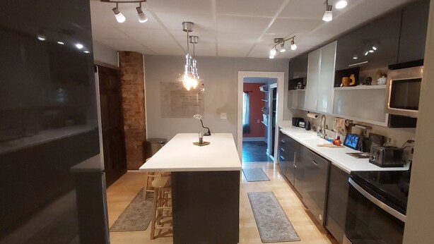 Een moderne keuken met een centraal eiland, inbouwapparatuur en hanglampen.