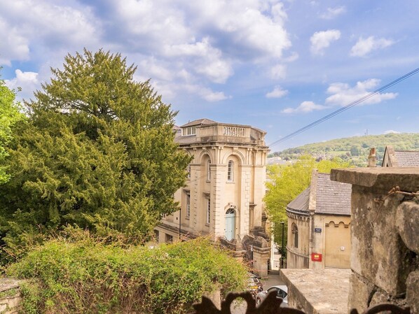 A historic building with classical architecture, surrounded by lush greenery and a clear sky.