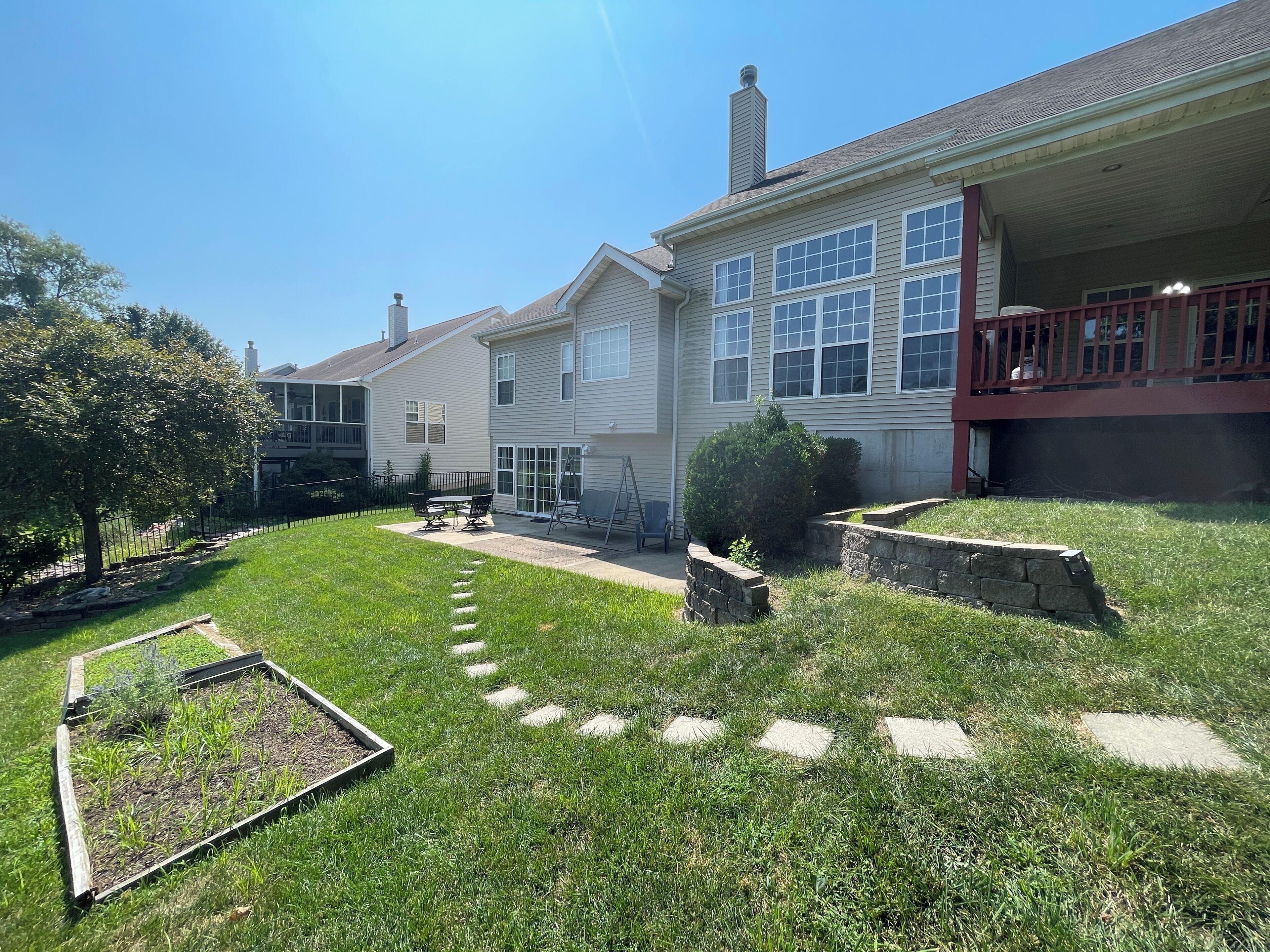 A residential property with a well-maintained lawn, a garden bed, and a patio area.
