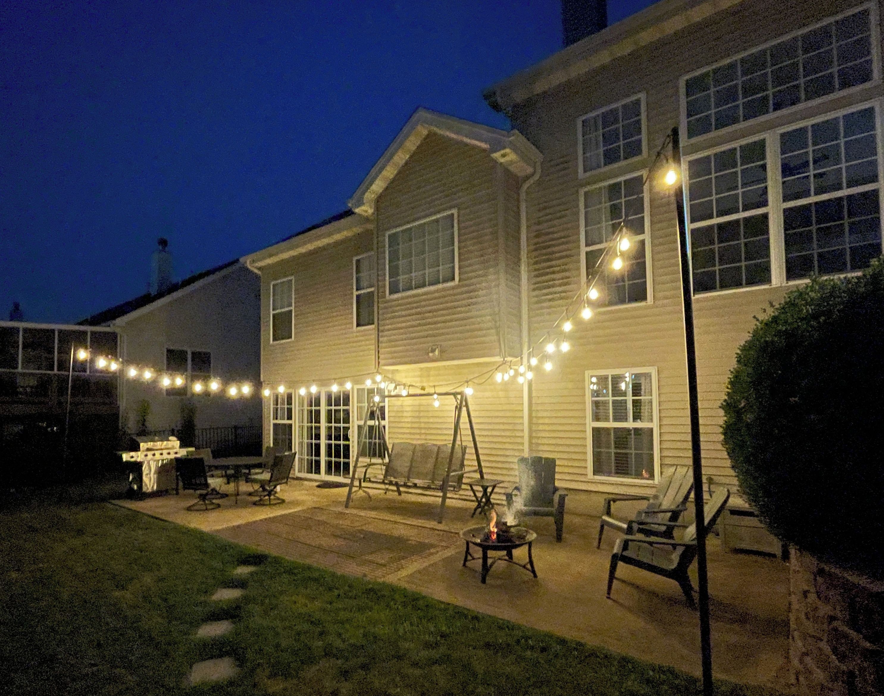 Un edificio residencial con un patio amoblado, que incluye muebles de exterior e iluminación colgante.
