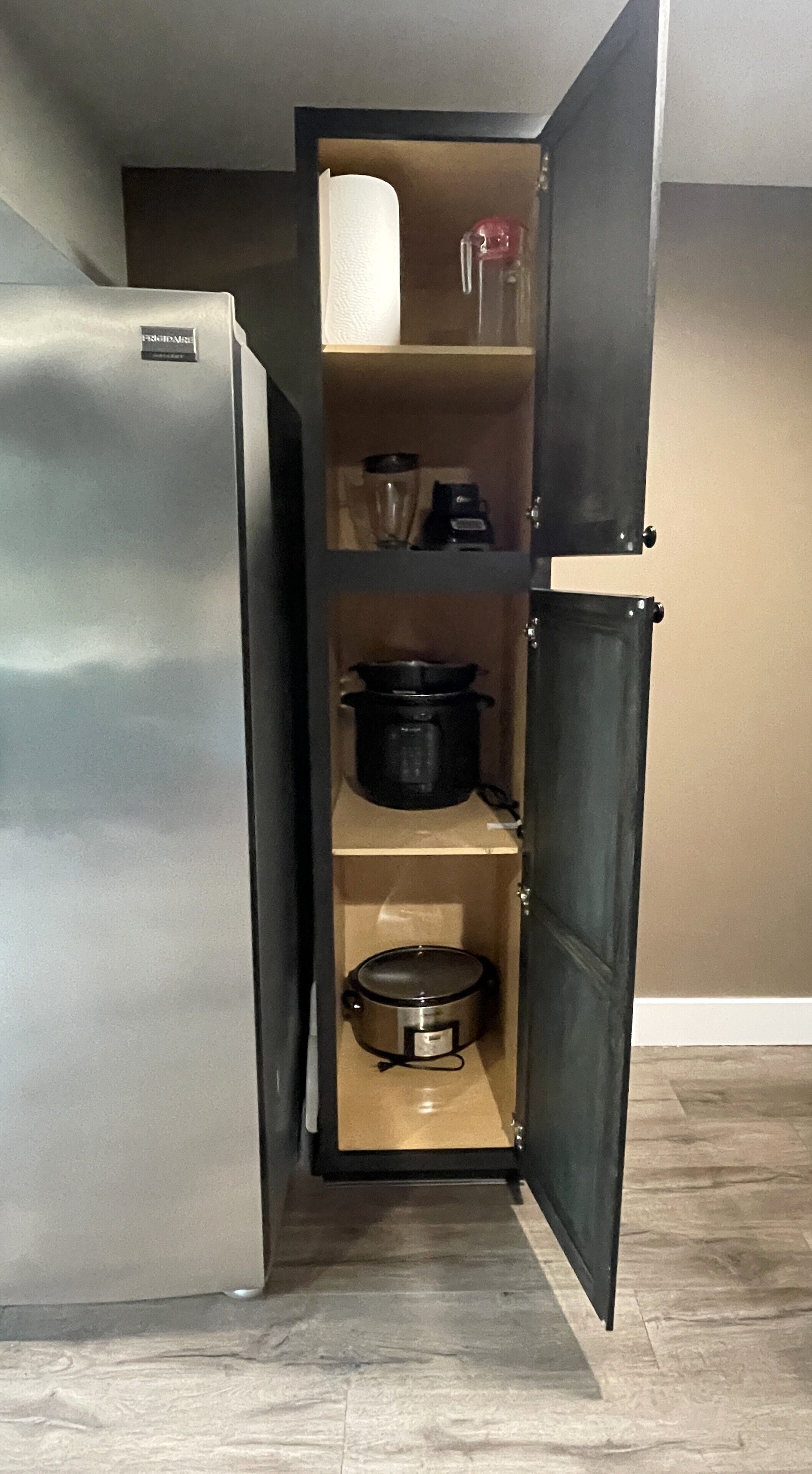 Uma cozinha compacta com geladeira embutida, micro-ondas na bancada e forno pequeno.
