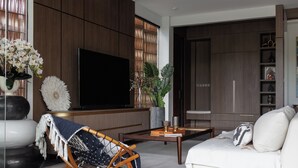 Una sala de estar moderna con sofá, mesa de centro, televisor y plantas decorativas.