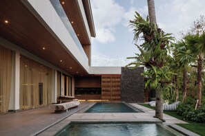 A modern building with a pool, outdoor seating, and tropical plants. - Lila Villa Pererenan - Bali Invest Club (Canggu)