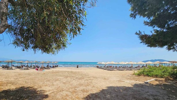 A beach with sun loungers and umbrellas, a clear sky, and a calm sea. - Casa Di Mare Artemis,near airport,near sea (Artemis)
