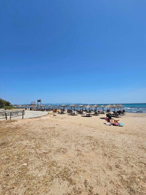 A beach with sun loungers and umbrellas, a lifeguard tower, and the ocean in the background. - Casa Di Mare Artemis,near airport,near sea (Artemis)