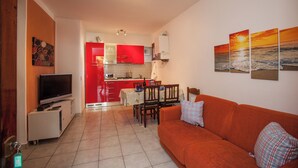 A compact living space with a kitchen, dining area, and a sofa. - Charming 2-room Apartment in a Peaceful Residential Area (Rosolina)